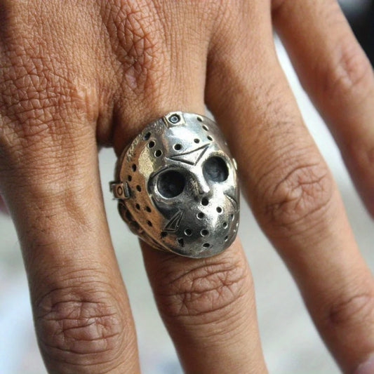 Silver mask ring on a finger with a blurred background