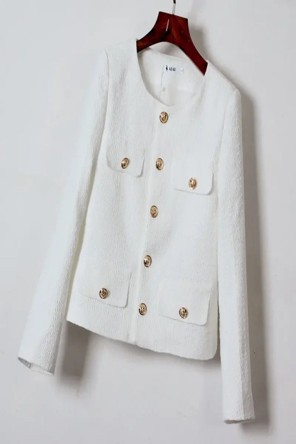 White jacket with gold buttons on a hanger against a white background