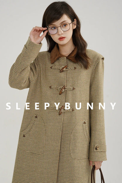 Woman wearing a plaid coat with 'Sleepy Bunny' branding on a gray background