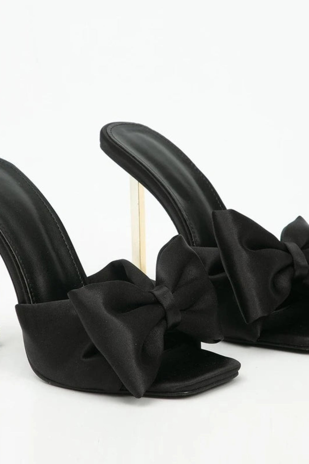 Black high-heeled shoes with bow details on a white background