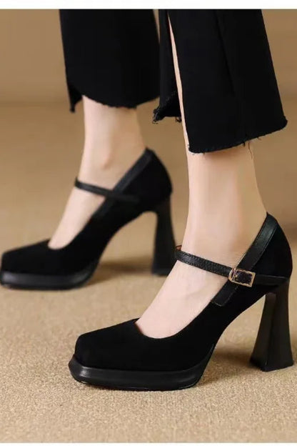 Black high-heeled shoes with a strap worn by a person on a beige background