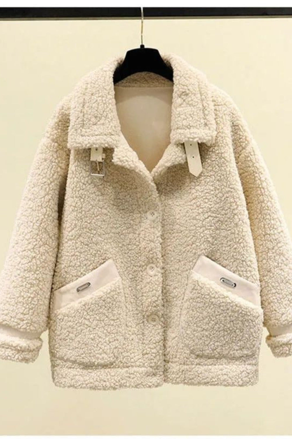 Beige sherpa jacket on a hanger against a beige background