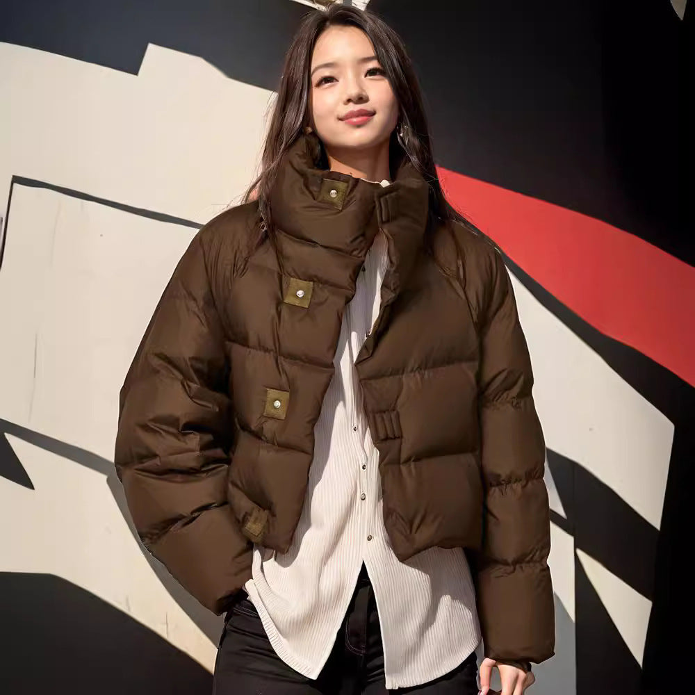 Woman wearing a brown puffer jacket in front of a colorful abstract wall.