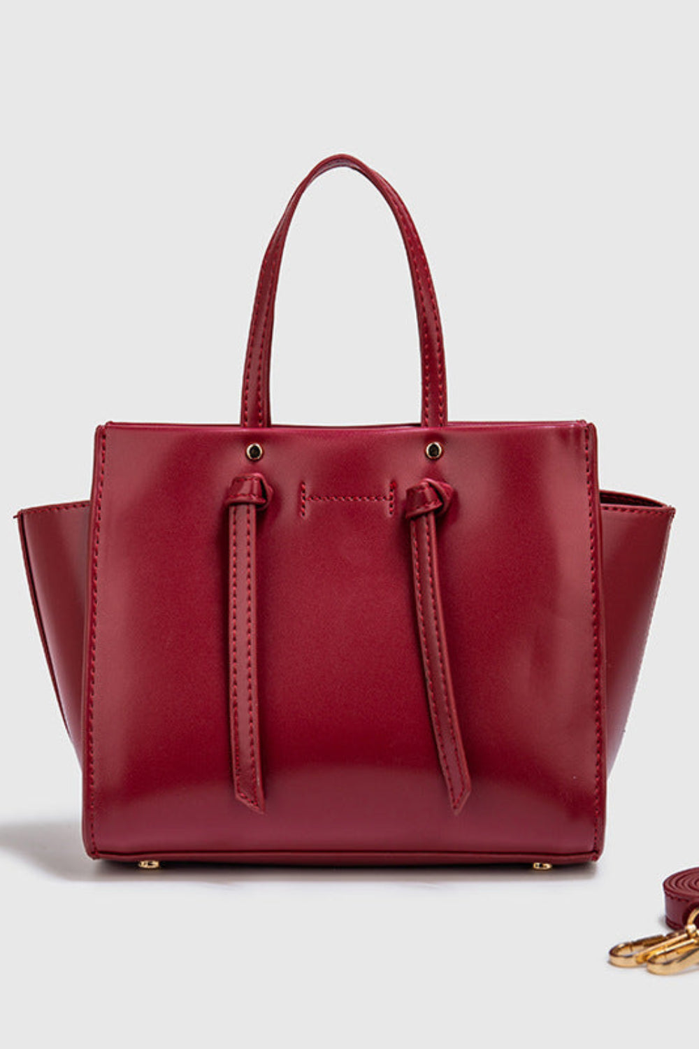 Red handbag with matching strap on a light gray background