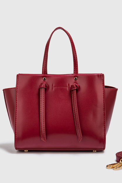 Red handbag with matching strap on a light gray background