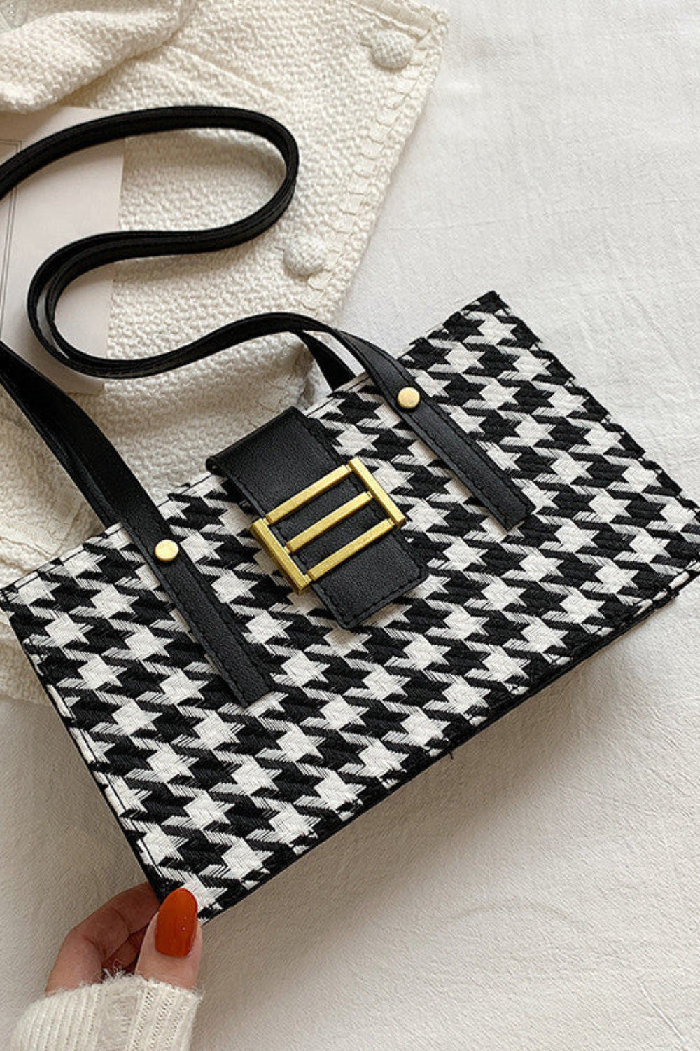Black and white checkered handbag with gold buckle on a light background