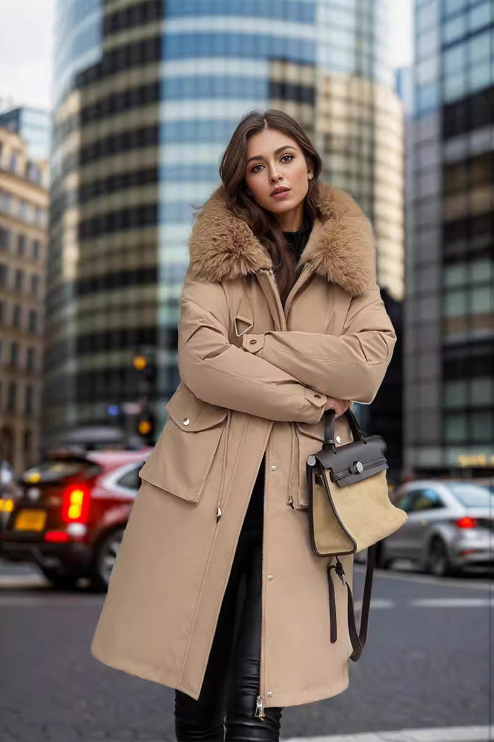 Woman in a beige coat with fur collar standing on a city street.