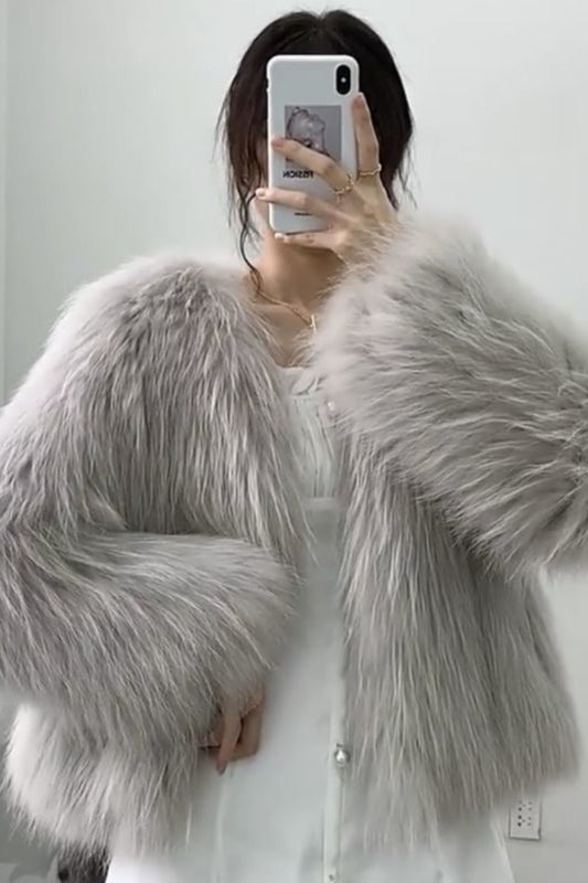 Person wearing a fluffy gray shawl taking a mirror selfie.