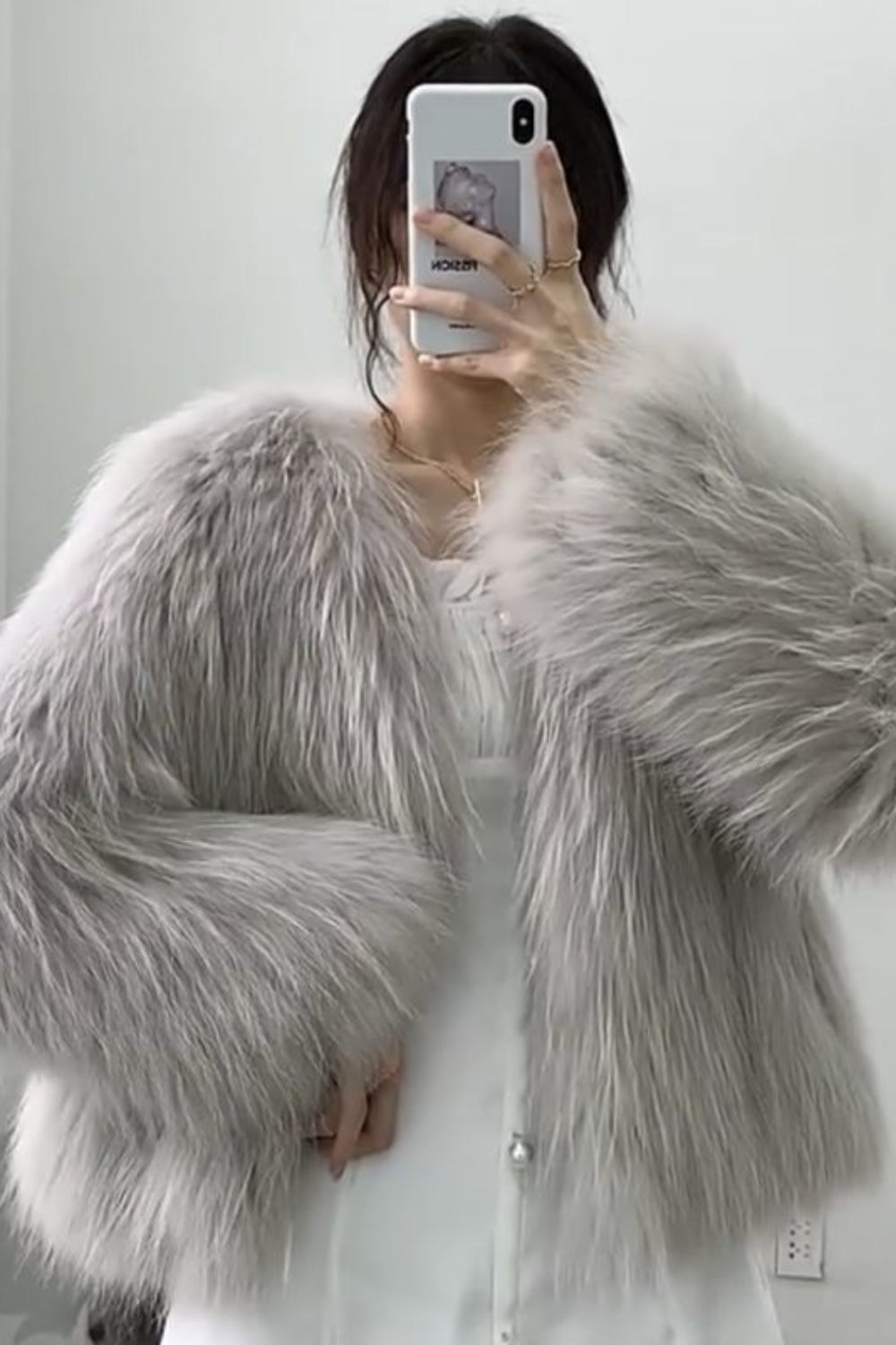 Person wearing a fluffy gray shawl taking a mirror selfie.