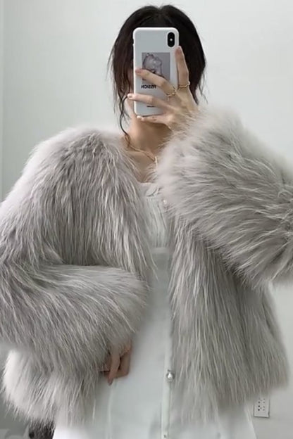 Person wearing a fluffy gray shawl taking a mirror selfie.