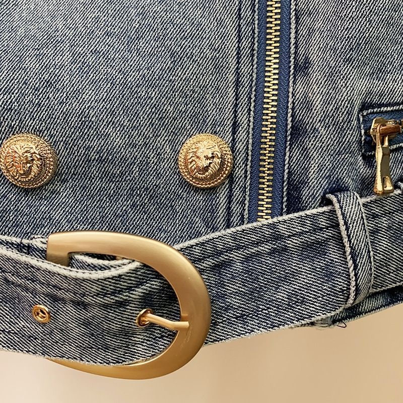 Close-up of a denim jacket with gold buttons and buckle on a beige background