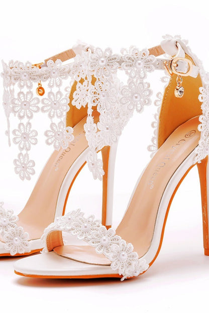 White high-heeled shoes with floral lace details on a white background