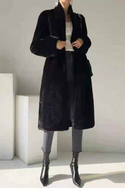 Person wearing a black coat in a minimalistic setting