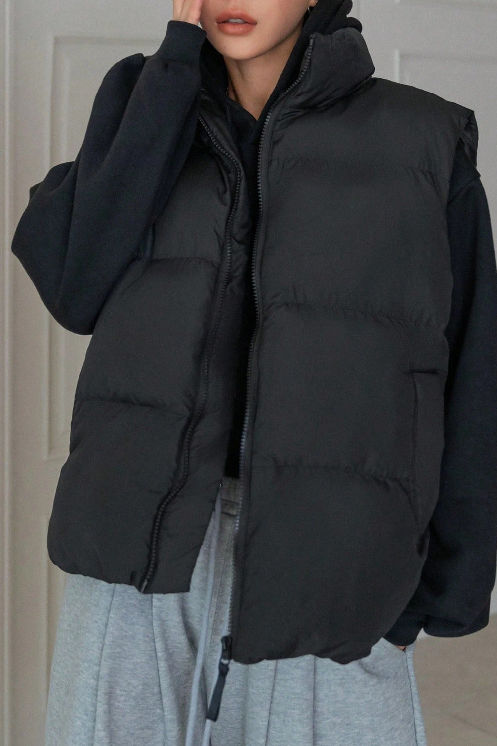 Person wearing a black puffer vest with a neutral background