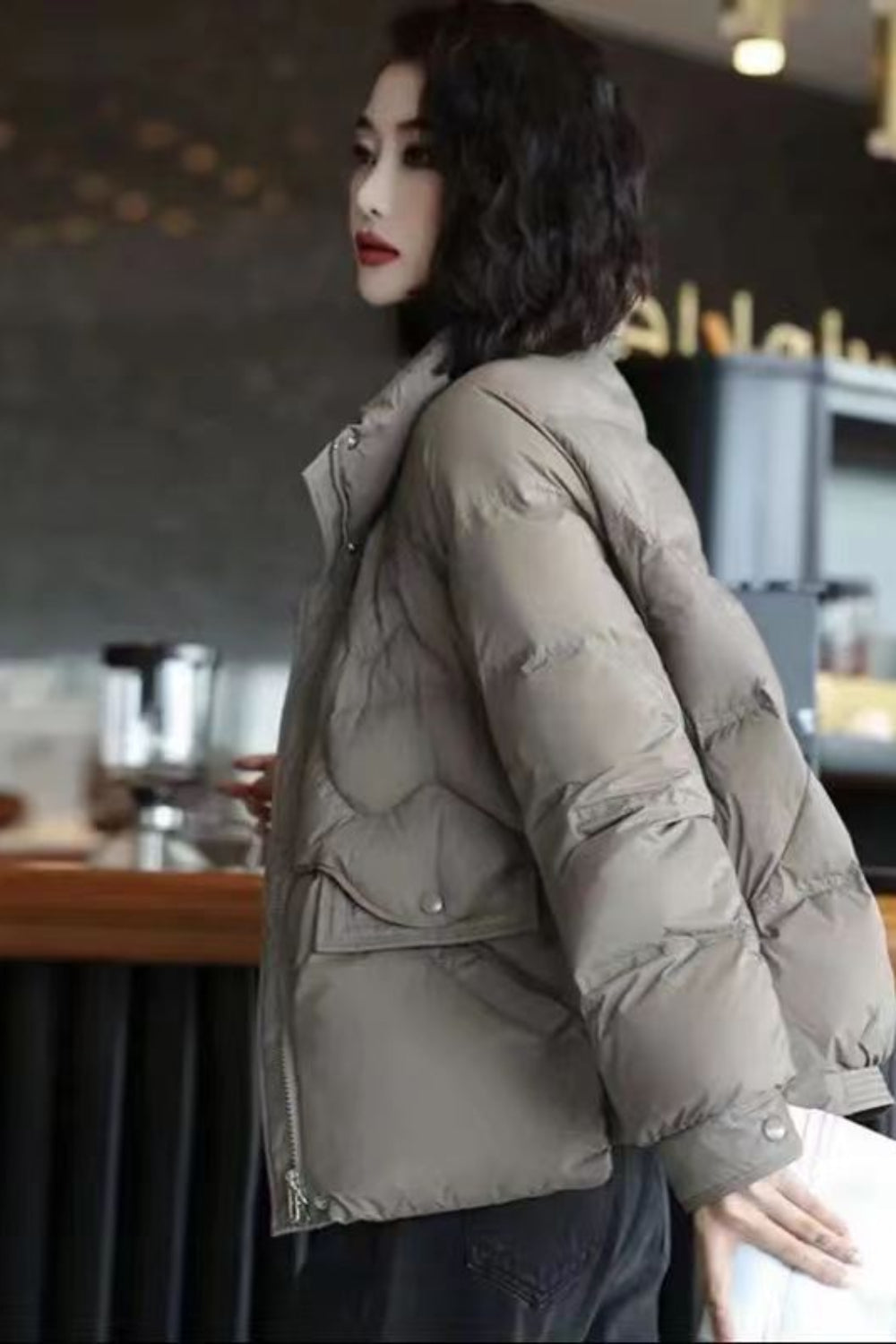 Woman wearing a beige puffer jacket in an indoor setting