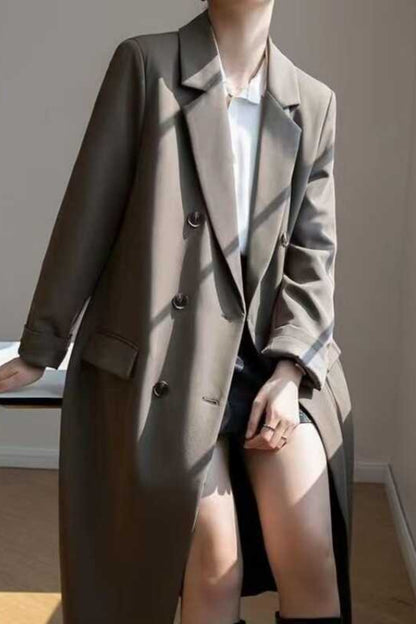 Person wearing a long coat in a room with a window