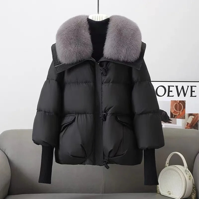 Black puffer jacket with gray fur collar on a gray sofa