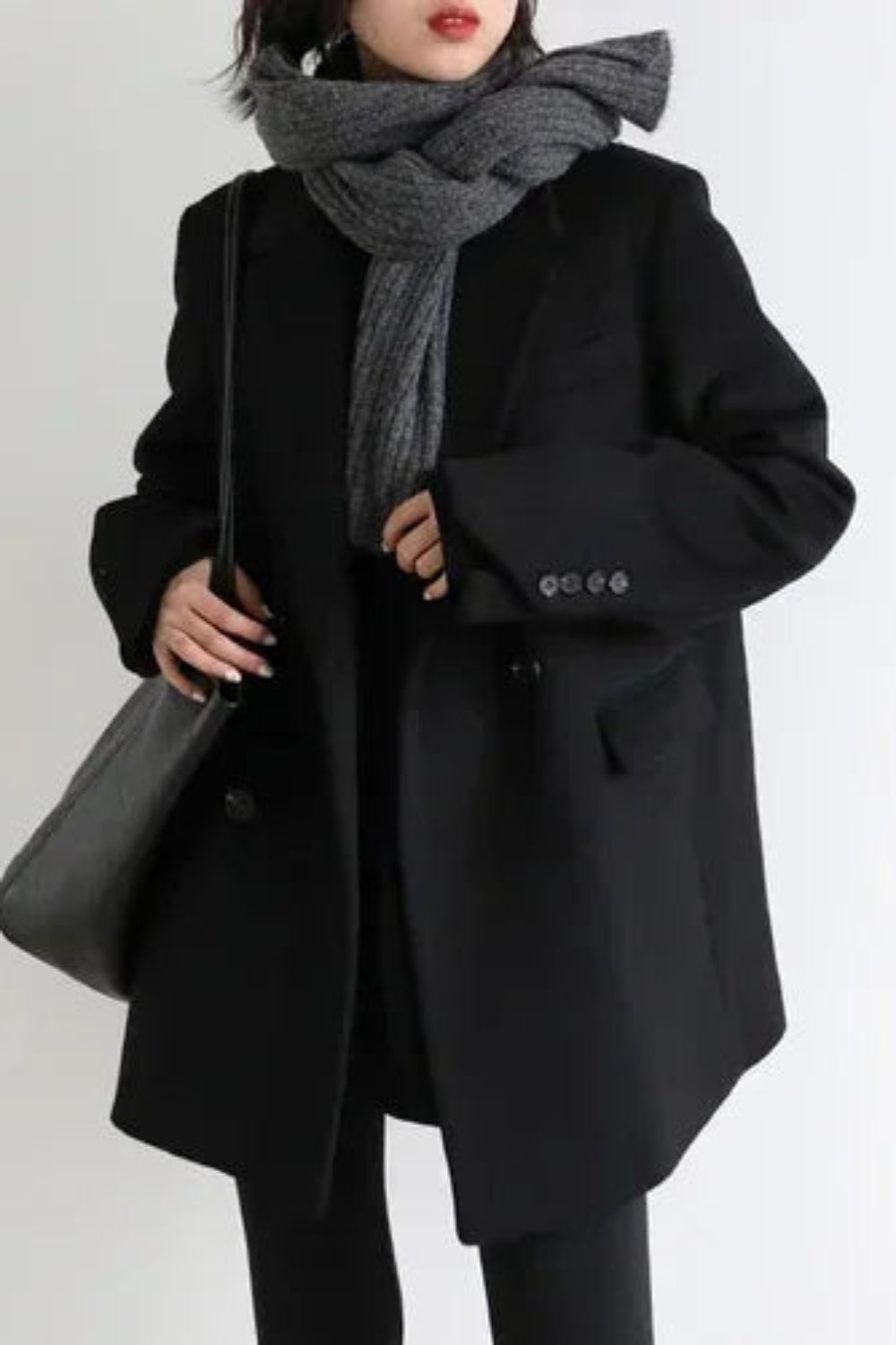 Person wearing a black coat and gray scarf on a white background
