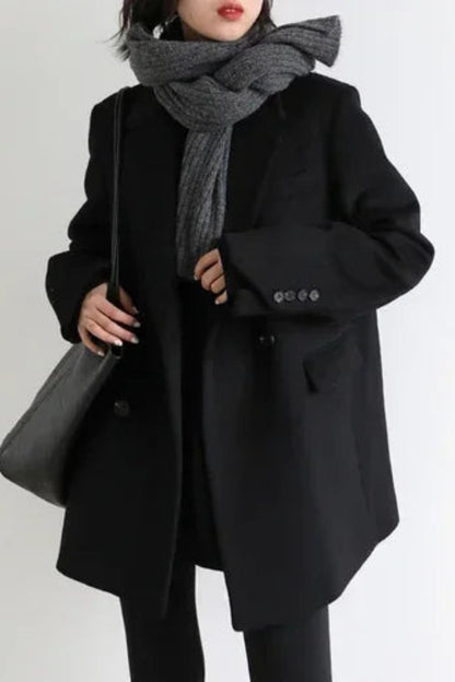 Person wearing a black coat and gray scarf on a white background