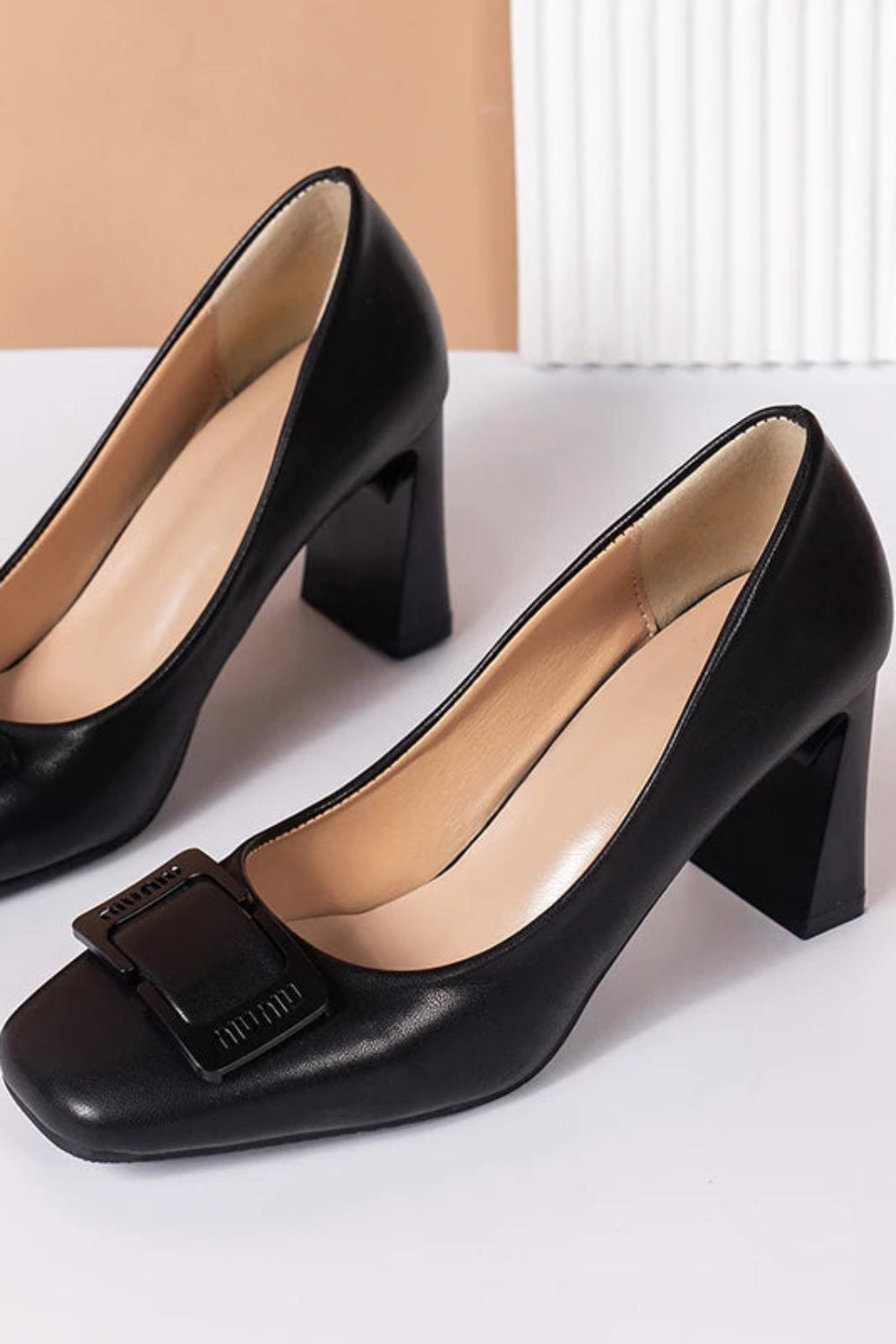 Black high-heeled shoes with buckles on a white surface