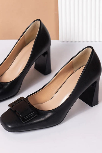 Black high-heeled shoes with buckles on a white surface
