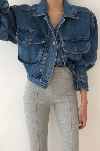 Person wearing a blue denim jacket and gray pants on a plain background