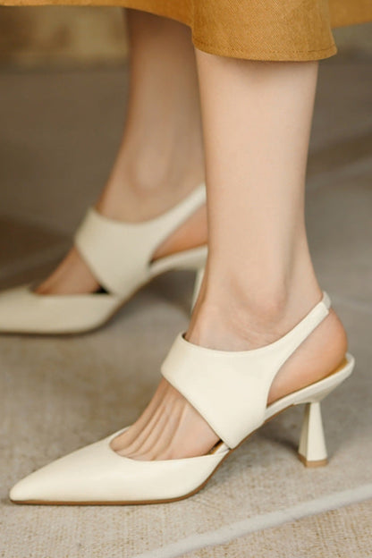 Beige high-heeled shoes worn by a person on a neutral background