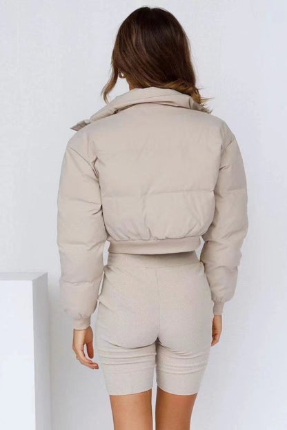 Person wearing a beige puffer jacket and shorts set on a white background