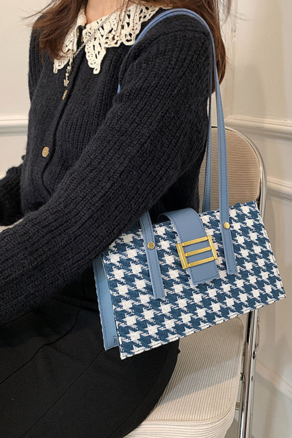 Person holding a blue and white patterned handbag with a gold clasp.