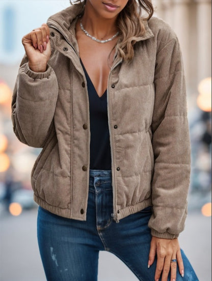 Person wearing a beige corduroy jacket with a blurred city street background