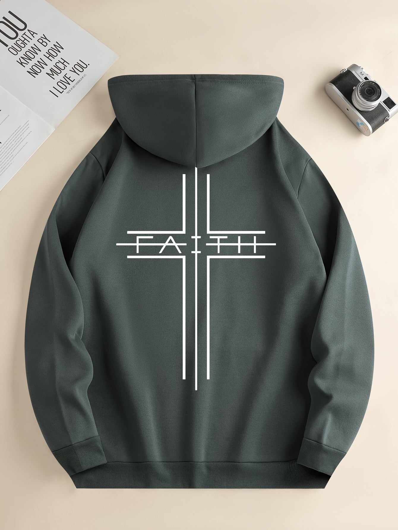 Dark gray hoodie with a white cross and 'FAITH' text on a beige background
