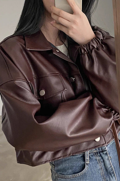 Person wearing a brown leather jacket and blue jeans indoors.