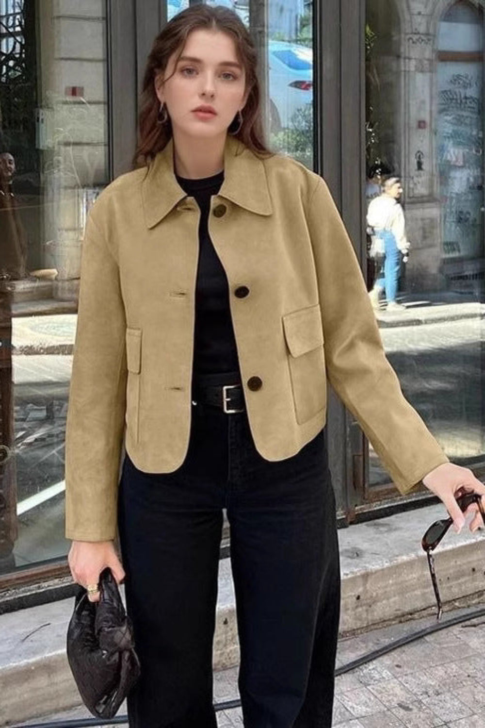 Woman in a beige jacket standing on a city street