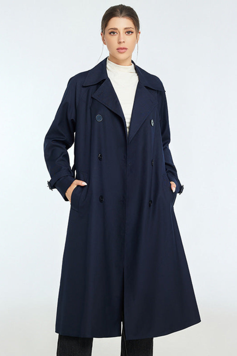 Woman wearing a navy blue trench coat on a white background