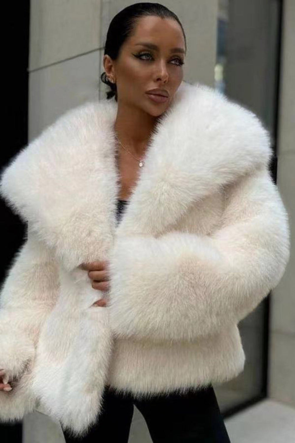 Woman wearing a white fur coat in an urban setting
