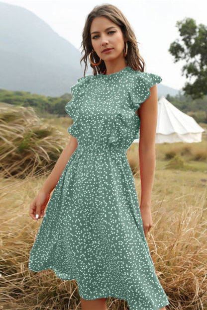 Woman in a green dress standing in a field with a tent in the background