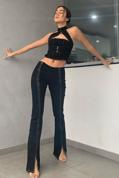 Woman in black halter top and high-waisted jeans posing indoors.