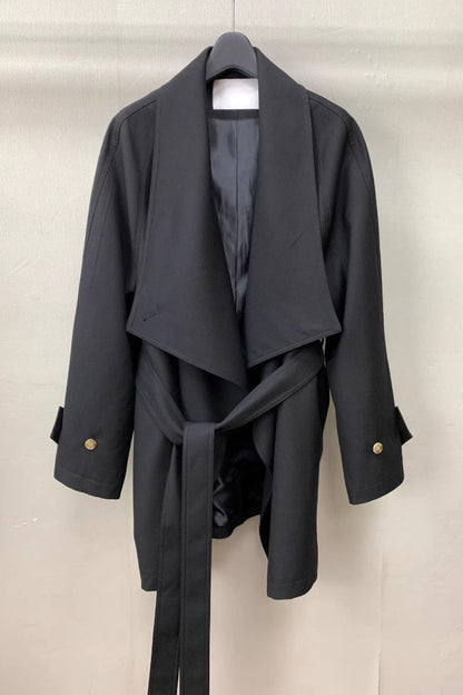 Dark gray coat with a belt on a hanger against a light background