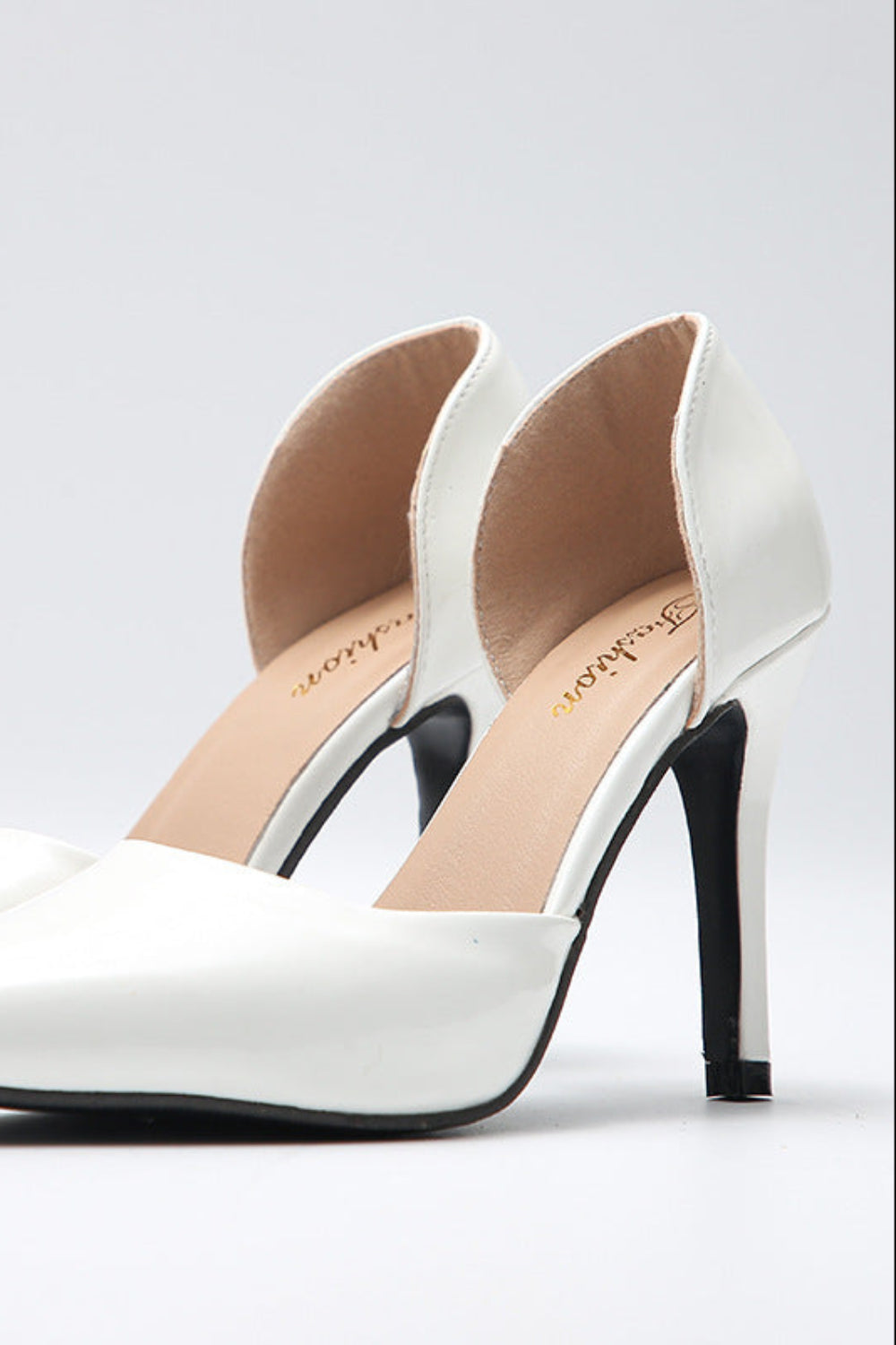 White high-heeled shoes with black soles on a light gray background