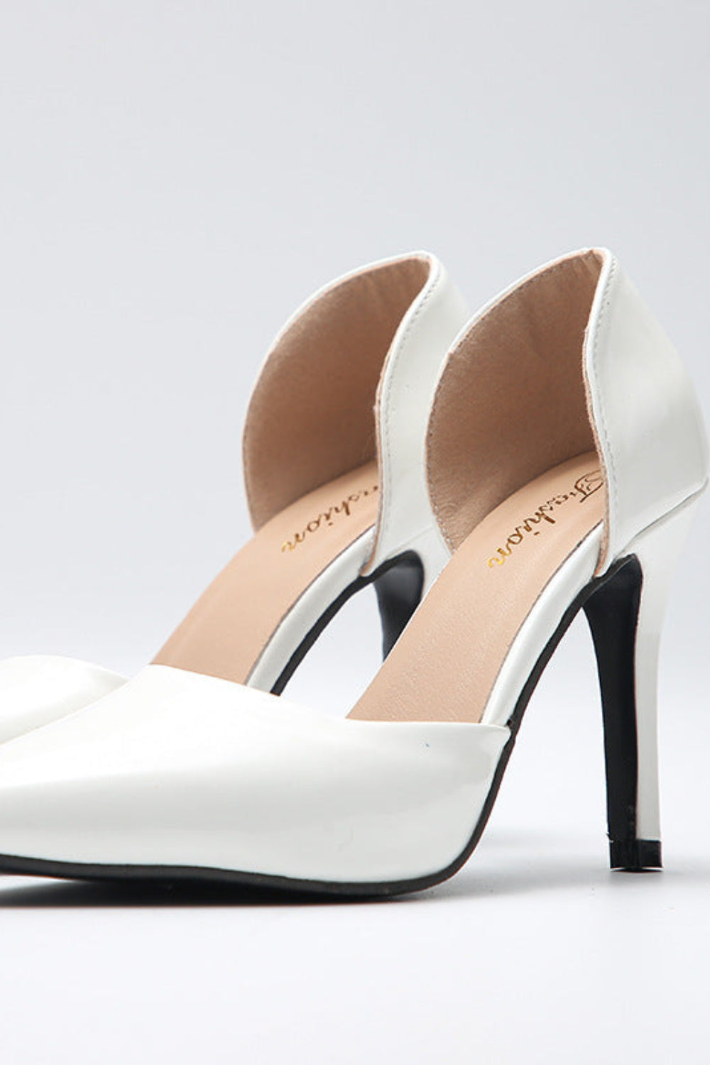 White high-heeled shoes with black soles on a light gray background