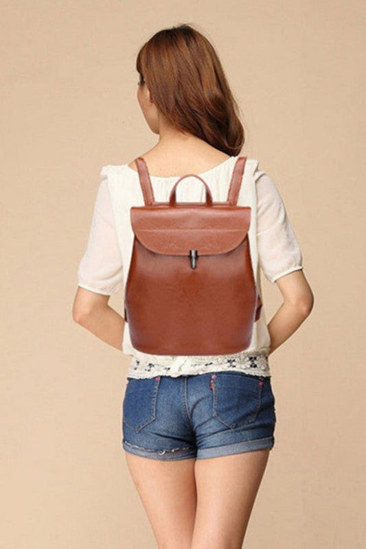 Woman wearing a brown leather backpack on a beige background