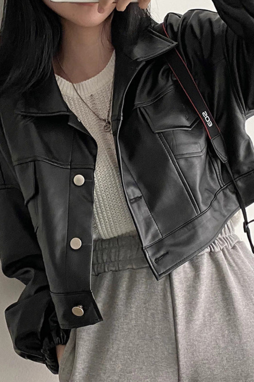 Person wearing a black leather jacket with a neutral background