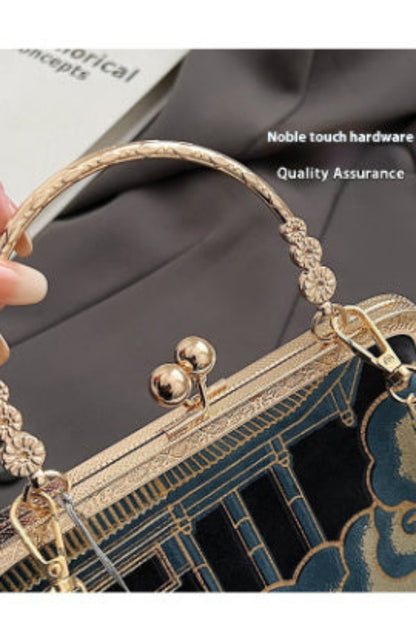 Gold handbag handle with decorative elements on a gray background