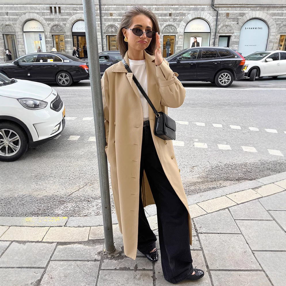 Woman in a beige trench coat standing on a city street