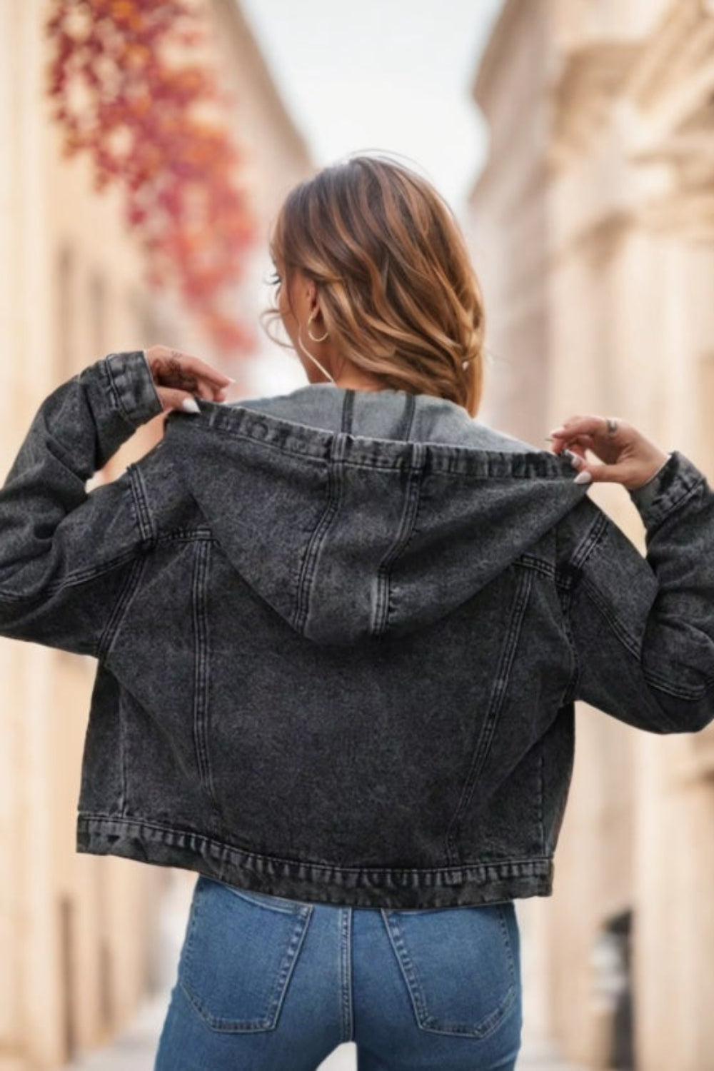 Person wearing a black denim jacket with a blurred background