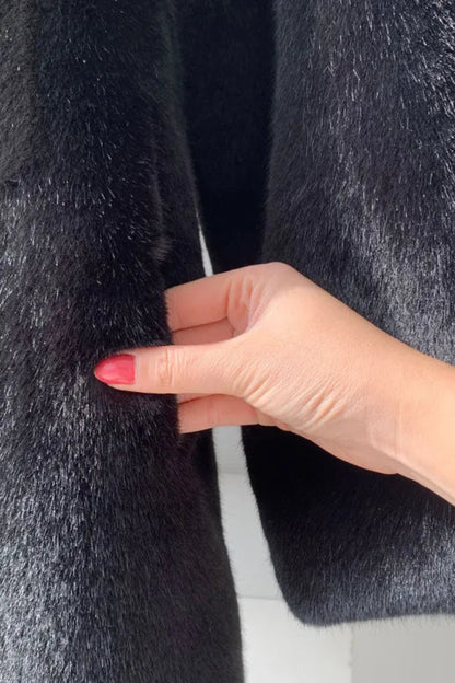 Hand with red nail polish touching a textured gray fabric