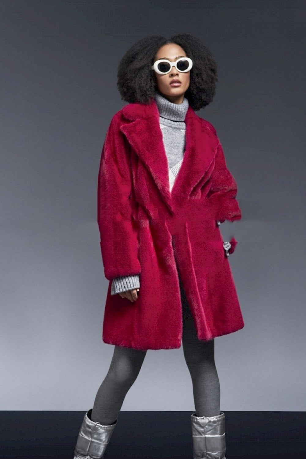 Person wearing a red coat, gray turtleneck, and silver boots on a gray background