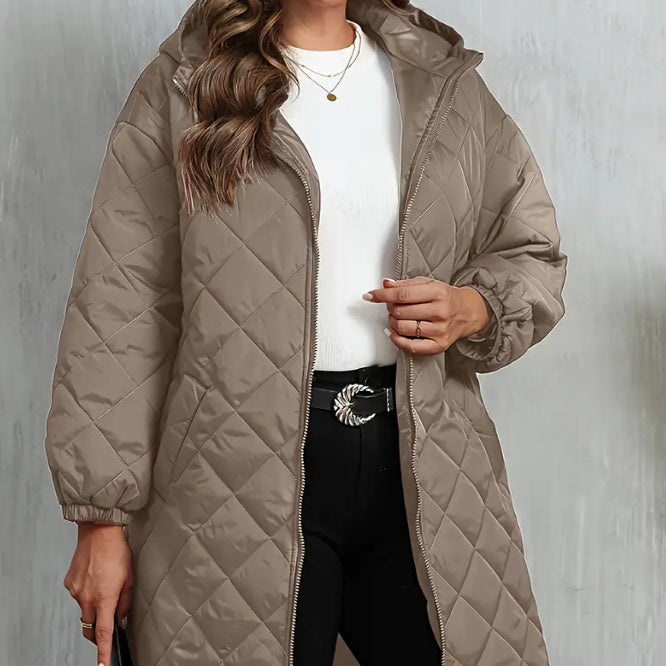 Person wearing a beige quilted coat against a plain background