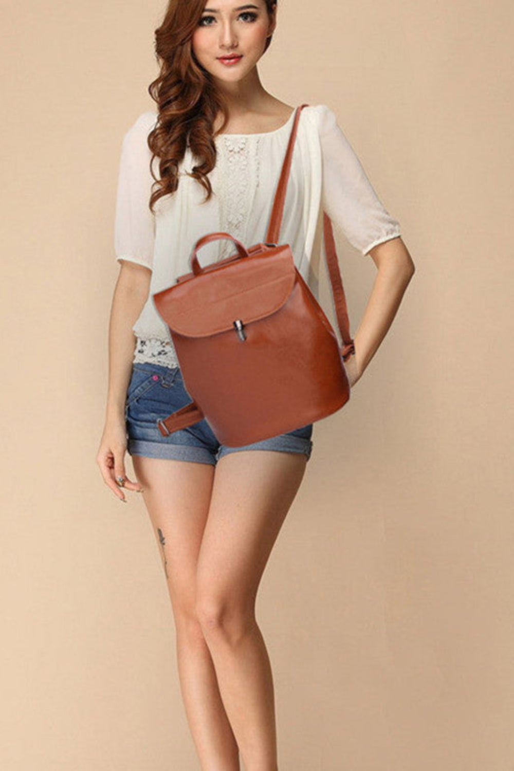 Woman holding a brown leather bag against a beige background