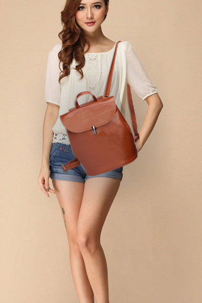 Woman holding a brown leather bag against a beige background